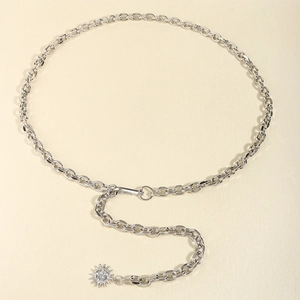 Detail of silver metal chain belt featuring oval links and a sunburst sun pendant charm