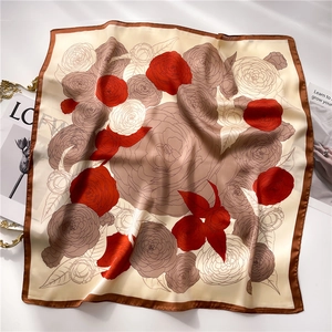 Detail of champagne silk scarf with red rose prints and brown rolled edges