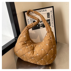 Detail der gesteppten Puffer-Tasche in Braun mit weißen Schleifen und Hobo-Form