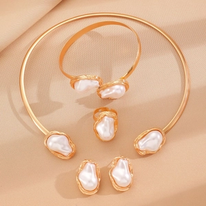 Detailed view of golden baroque pearl jewelry set with necklace and bracelet on silk