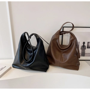 Detailed view of large black and dark brown soft leather hobo bags in an indoor setting