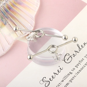 Detail of silver industrial barbell piercing with a butterfly zircon pendant on props