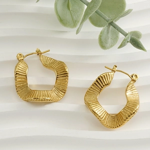 Close-up of golden geometric earrings with vertical textured finish on a white background