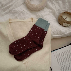 Detail of burgundy polka dot mid-calf socks with blue ribbed cuffs on knitwear background