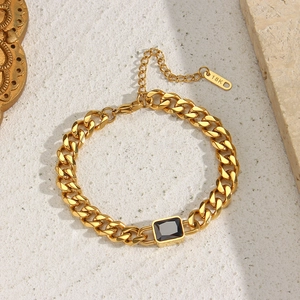 Macro detail of 18K gold-plated Cuban chain with a black rectangular stone and logo tag
