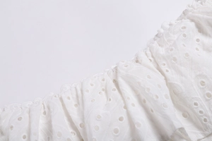 Gros plan de tissu en coton blanc avec broderie anglaise délicate et ajourée