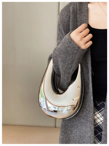 Close-up of a silver mirror acrylic clutch bag with a unique crescent drop shape