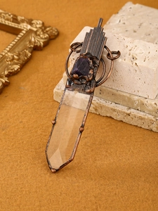 Detail of vintage bronze pendant with white crystal point and raw amethyst stone