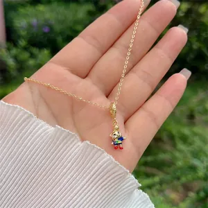 Detail van een 18K vergulde ketting met een kleurrijke beer hanger, getoond op de hand