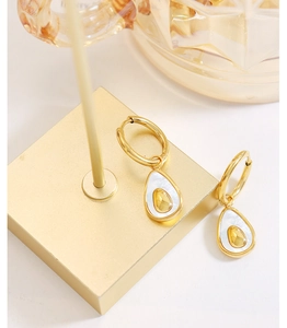 Detail of avocado earrings with white shell inlay on a golden display stand
