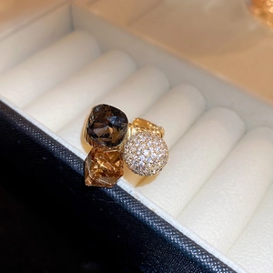 Detail of gold-plated ring with grey and champagne crystals and a white zircon paved ball