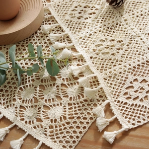 Beige cotton crochet table runner with hollow floral lace pattern and tassel fringe
