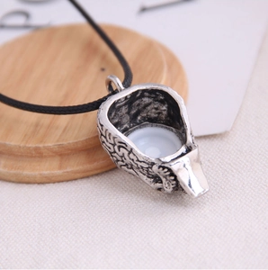 Macro shot of retro silver spoon pendant with white inlay and aged texture detail