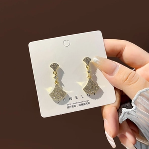 Detailed close-up of fan-shaped pavé earrings with S925 silver needles and gold finish