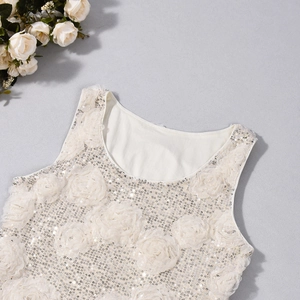 Detail of white sleeveless top featuring sequins and 3D floral appliqués with a round neck