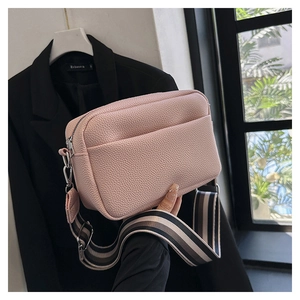 Detail of light pink pebble leather crossbody bag with stylish striped wide strap