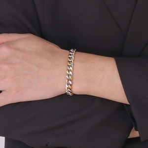 Gros plan d'un bracelet gourmette bicolore or et argent sur le poignet d'un mannequin