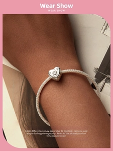 Detail of silver heart charm with sparkling zircons on a mesh bracelet band