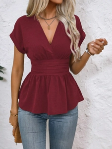 Close-up of a burgundy V-neck top featuring pleated waist detail and rolled-up sleeves