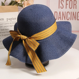 Detail of navy straw hat with yellow striped bow ribbon on elegant craft background