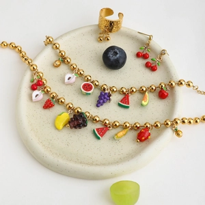 Macro shot of 18K gold plated fruit charm necklace jewelry set on ceramic plate