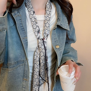 Detail of black and white paisley silk scarf necklace worn with casual denim jacket