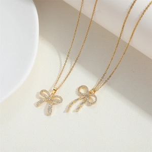 Élégant collier nœud doré serti de zircons avec de délicats pendentifs à franges