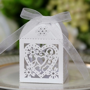 Close-up of white laser-cut heart candy box with ribbon on a decorative porcelain plate