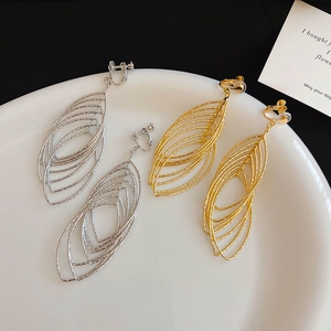 Detail of gold and silver hollow oval spiral ear clips on a white ceramic plate