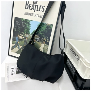 Detail of a black minimalist nylon dumpling bag styled in an industrial setting
