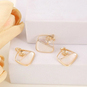 Detailed view of gold rhombus pendants with mother of pearl inlay and zircon flower accents