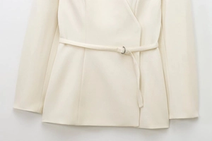 Detail of elegant beige wrap blazer featuring a matching waist belt with metal buckle