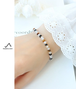 Détail du bracelet en perles de jade blanc, œil de tigre et séparateurs en acier inoxydable or