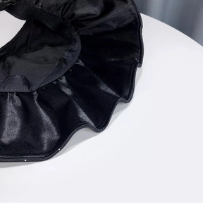 Detailed close-up of the black satin fabric texture and ruffle edge of the sun hat