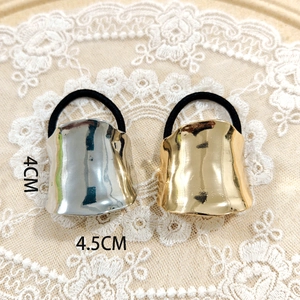 Close-up of gold and silver wavy alloy hair ties on lace background with 4cm size markers