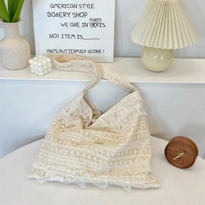 Close-up of cream lace tote bag with intricate floral crochet patterns and a soft texture