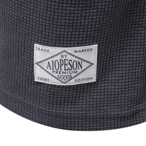 Detail of dark gray waffle knit fabric texture and premium stitched brand label on shorts