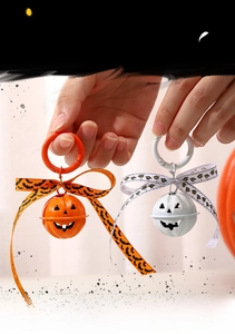 Detail of Halloween pumpkin bell keychains in orange and white with bat print ribbons