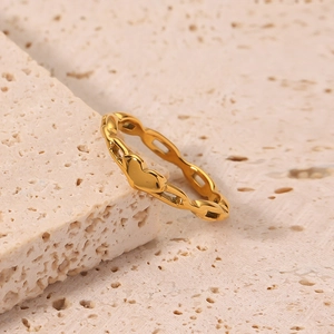 Polished 18K gold hollow chain ring with heart design on natural stone display