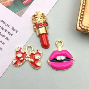 Close-up of alloy lipstick, bow, and lips charms for DIY jewelry making with gold accents