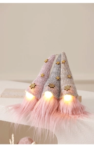 Set of three glowing Christmas gnomes with LED lights and sequined hats on white steps