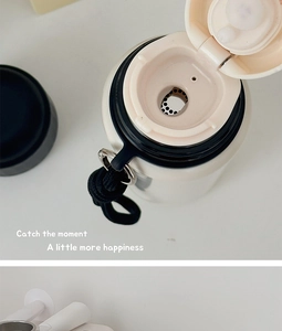 Detail view of the white stainless steel thermos lid with a black nylon carry strap