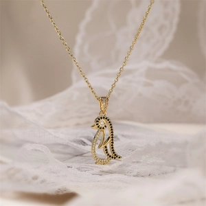 Macro shot of gold penguin pendant with black and clear zircon stones on delicate chain