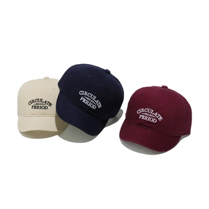 Detail of embroidered lettering on cotton baseball caps in beige, navy and burgundy