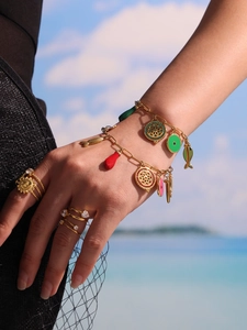 Detail of gold charms bracelets with colorful enamel and sun motif rings for summer