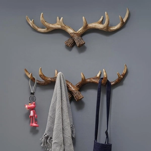 Vintage antler wall hooks in resin with keys, towel, and apron on gray wall background
