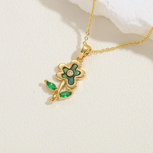 Macro shot of gold flower pendant with abalone shell petals and green leaf gems