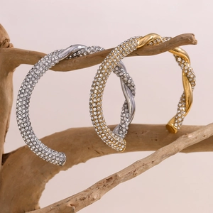 Detail von gedrehten Armreifen mit Pavé-Strasssteinen in Gold- und Silberoptik