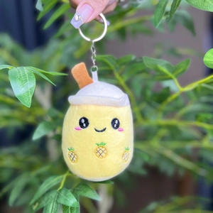 Detailed view of a yellow pineapple milk tea plush keychain with a metal ring