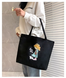 Detailed side view of a large black canvas tote bag with a cute cartoon girl print